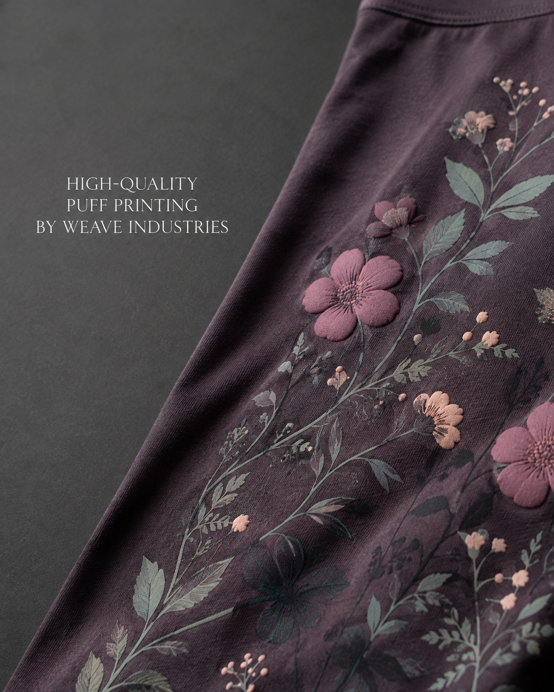 Close-up of a dark garment with raised pink floral printing and green leaf details.